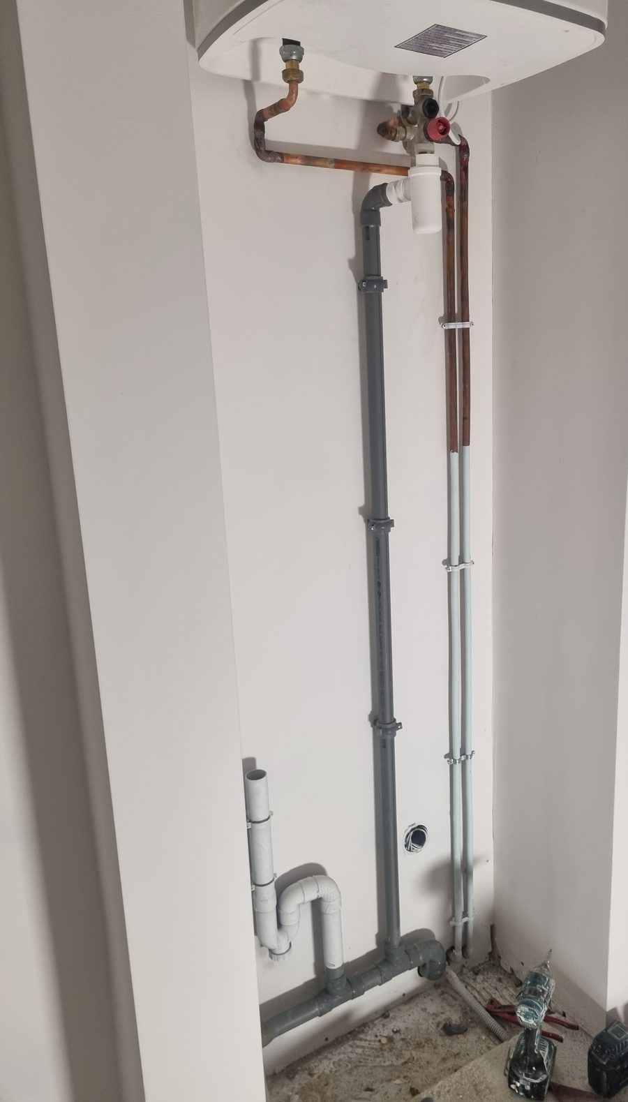 Alimentations cuivre et évacuation PVC sous un chauffe-eau vertical