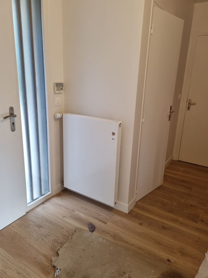 Radiateur panneau bas et robinet thermostatique posés dans une entrée