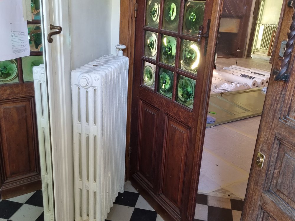 Radiateur fonte posé dans un hall d'entrée ancien à sol damier