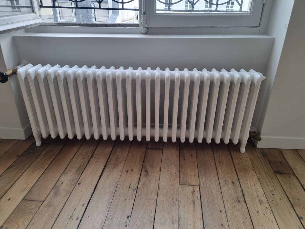 Radiateur fonte à colonnes remplacé sur parquet ancien dans un appartement parisien