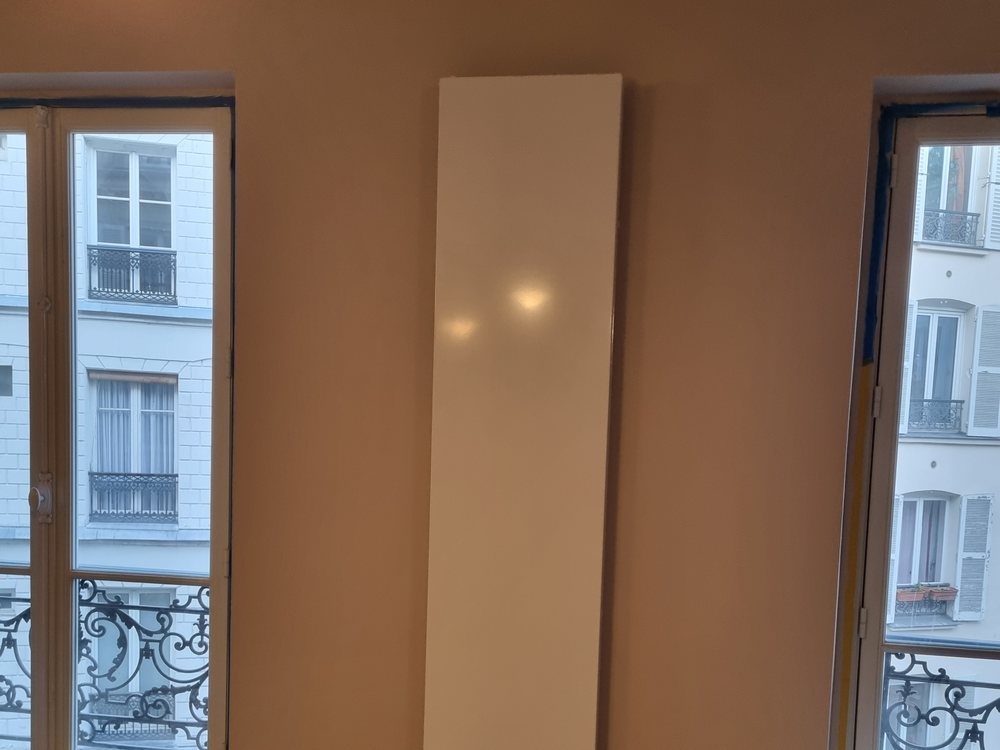 Radiateur vertical posé sur mur étroit entre deux fenêtres