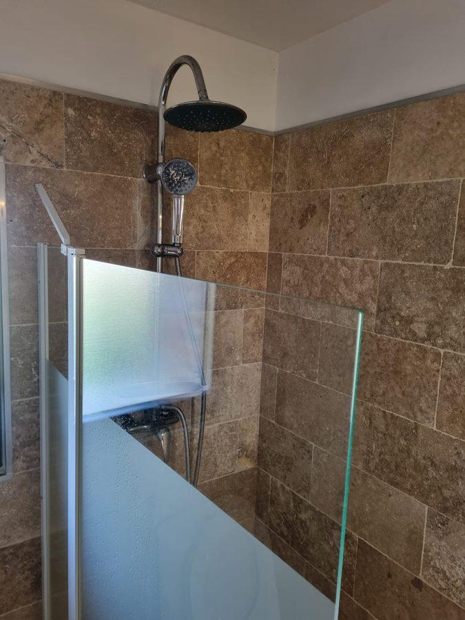Colonne de douche avec ciel de pluie posée sur mur travertin