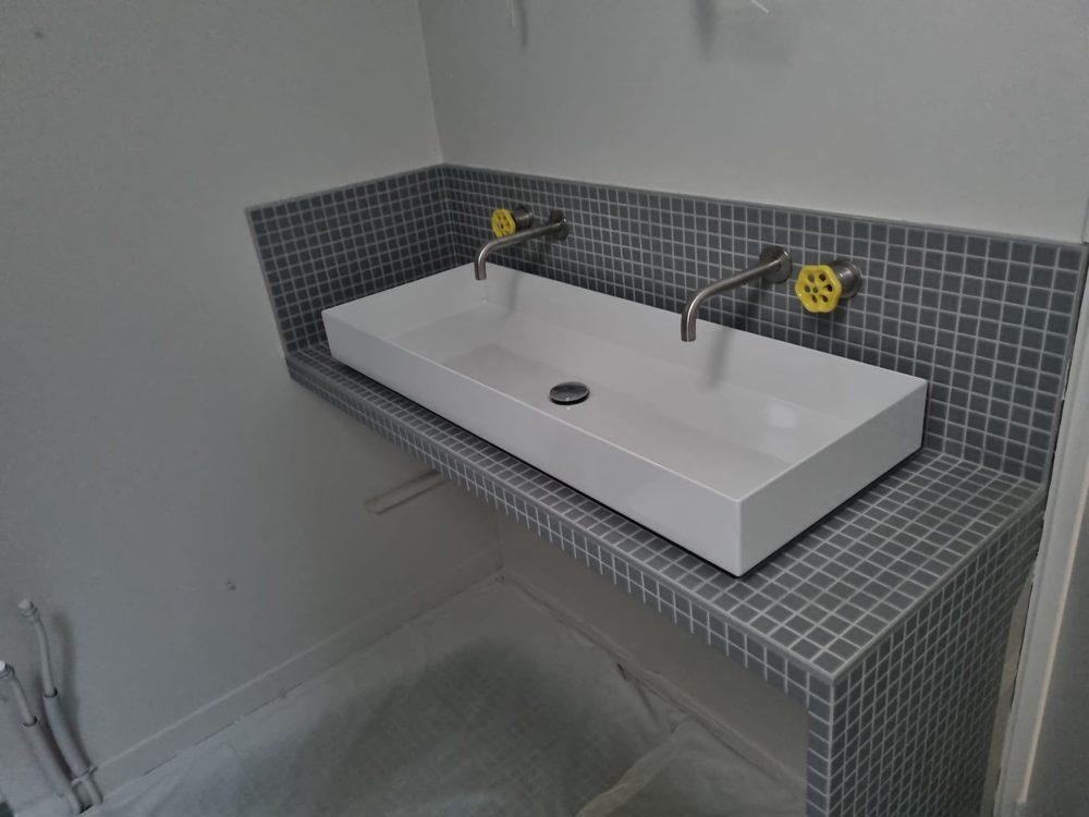 Plan vasque maçonné en mosaïque avec robinetterie murale