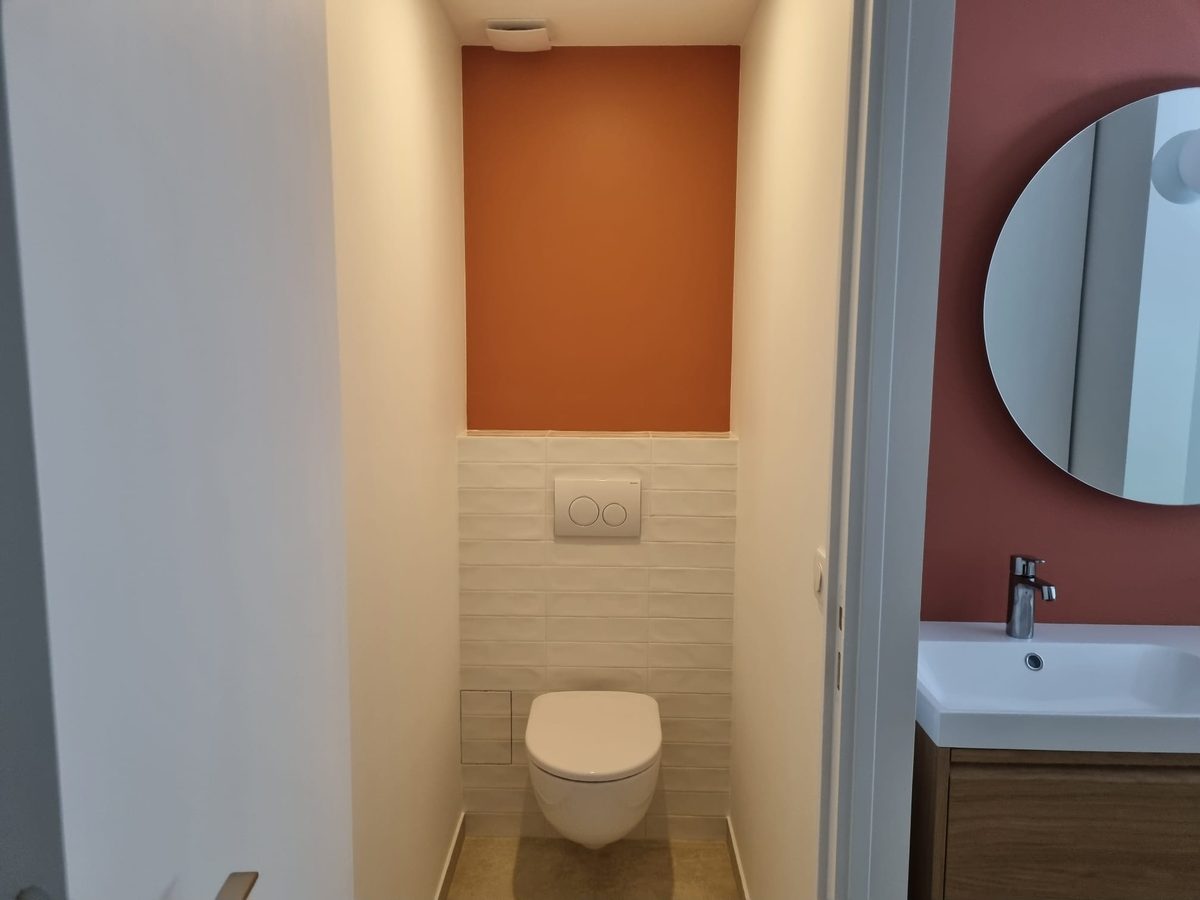 WC suspendu avec faïence blanche et mur orange