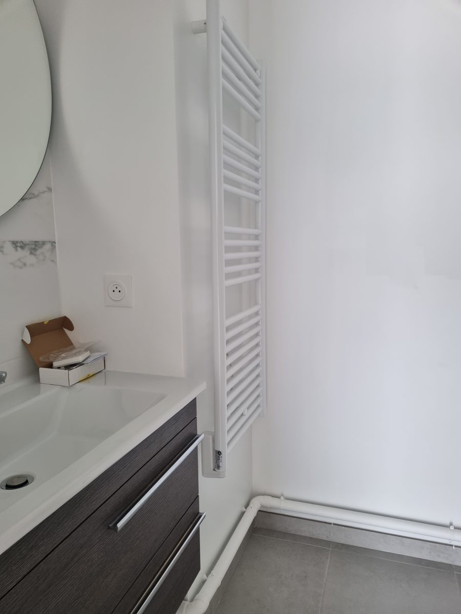 Meuble vasque et sèche-serviettes dans une salle de bain effet marbre