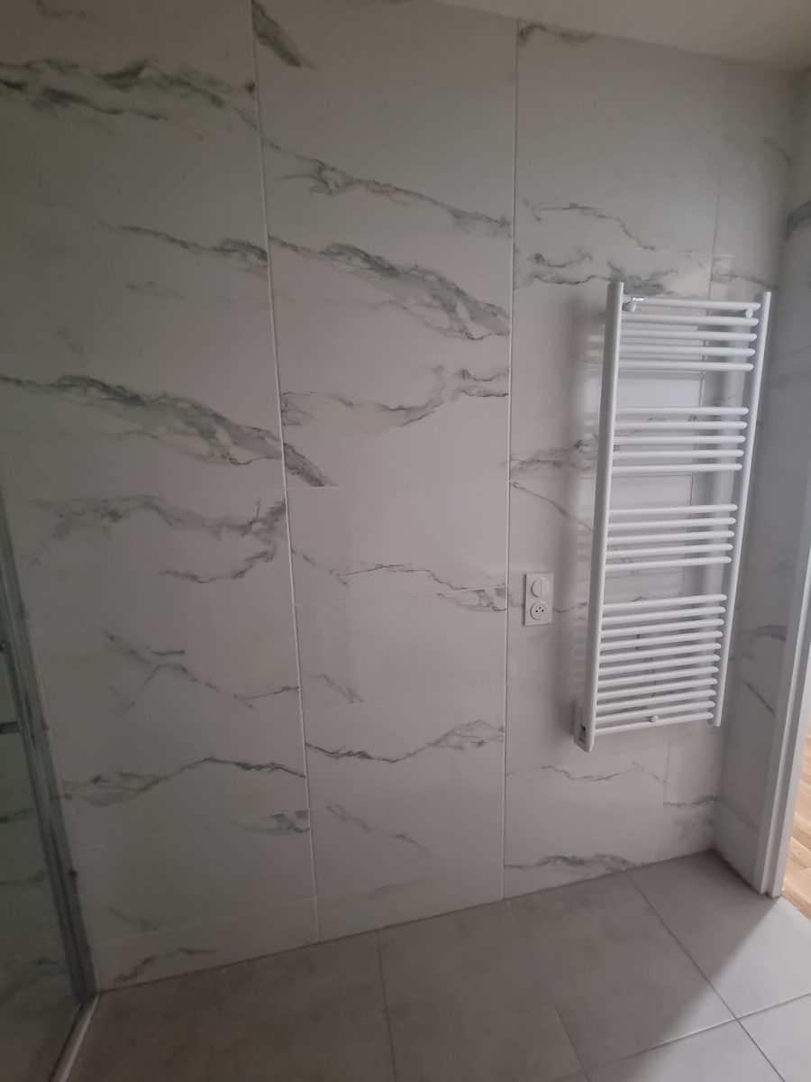 Sèche-serviettes et meuble vasque dans une salle de bain rénovée