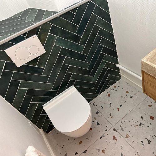 WC suspendu devant une faïence verte posée en chevrons