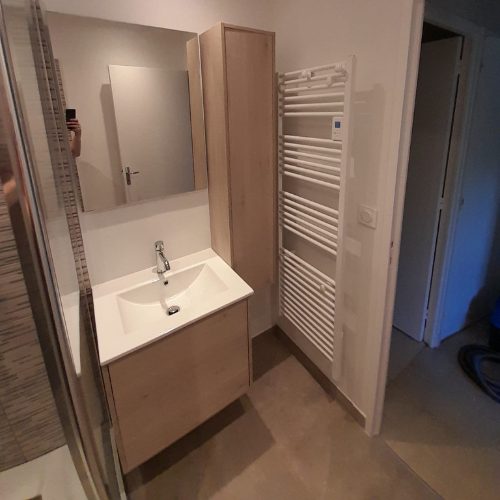 Sèche-serviettes posé à côté d’un meuble vasque en bois