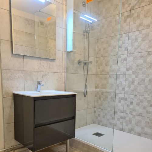 Meuble vasque et douche carrelée dans une salle de bain aux tons sable