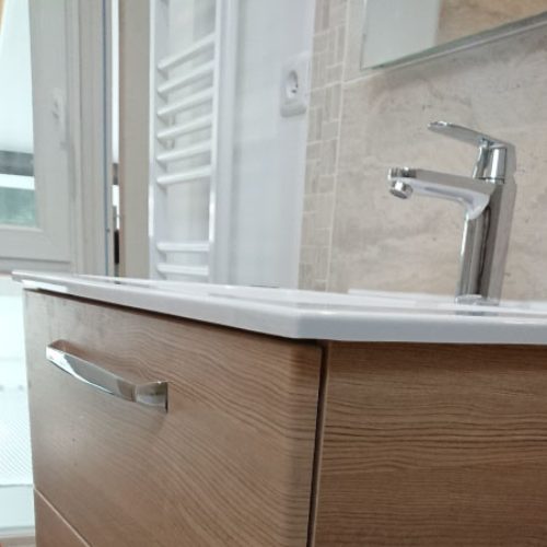 Meuble vasque bois et sèche-serviettes dans une salle de bain rénovée